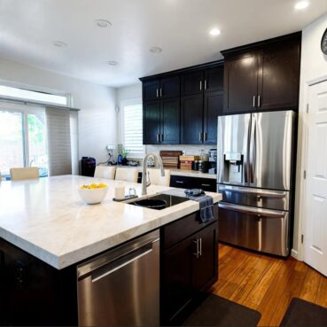 Clean home kitchen with dark cabinets and spotless island by Vieira Cleaning